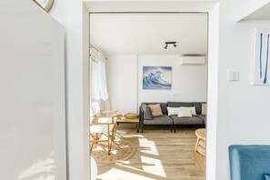 Een moderne woonkamer met een bank, een eettafel met stoelen, een rond tapijt en een schilderij aan de muur.