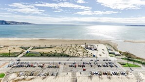 Vista aérea de un estacionamiento costero con una playa y el océano al fondo.