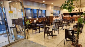 A restaurant with multiple tables and chairs, a cash register, and potted plants. - HOTEL KUNIMI KAMONOMIYA (Odawara)