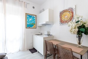 Una cucina compatta con angolo ristoro, un dipinto raffigurante una spiaggia e un'opera d'arte astratta moderna.