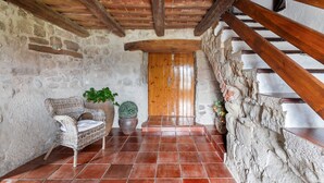 A rustic interior with a stone wall, wooden staircase, and a wicker chair. - Country House 'Casamira' with Mountain View, Private Pool and Wi-Fi (Unknown)