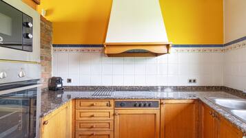 Eine Küche mit Holzschränken, einem Backofen, einer Mikrowelle und einer Dunstabzugshaube.