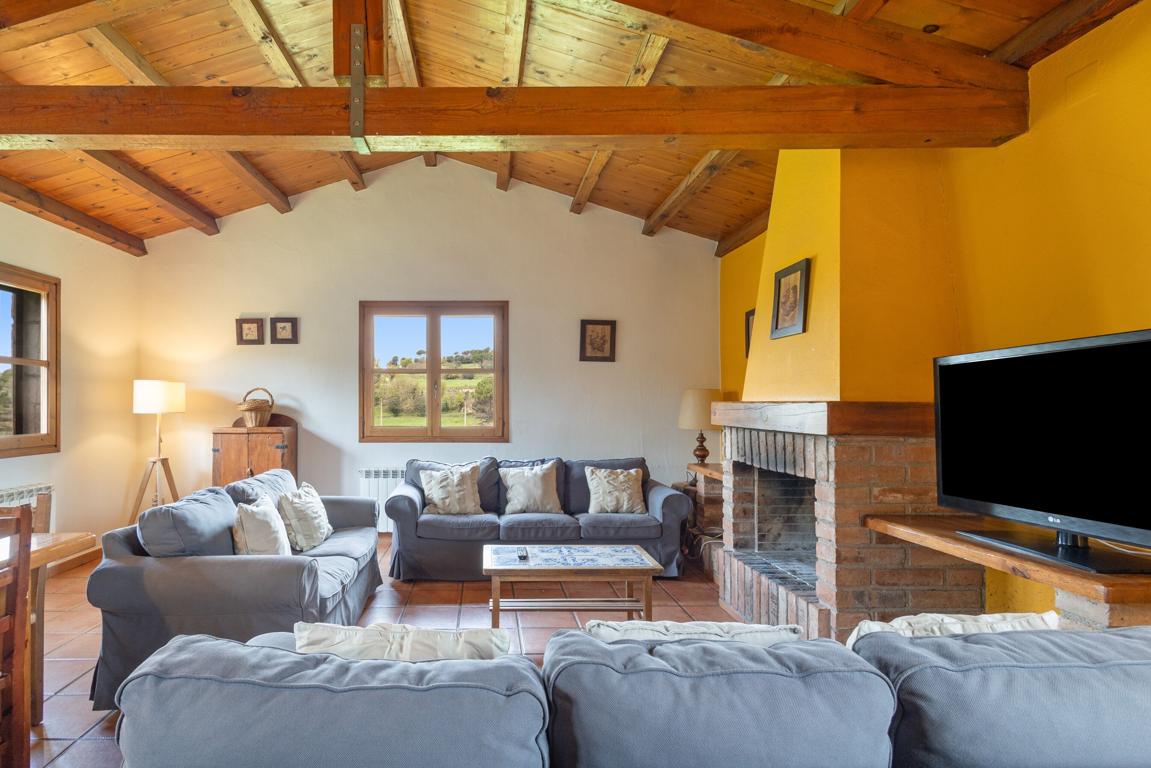 A living room with a fireplace, two sofas, a television, and a window with a view.