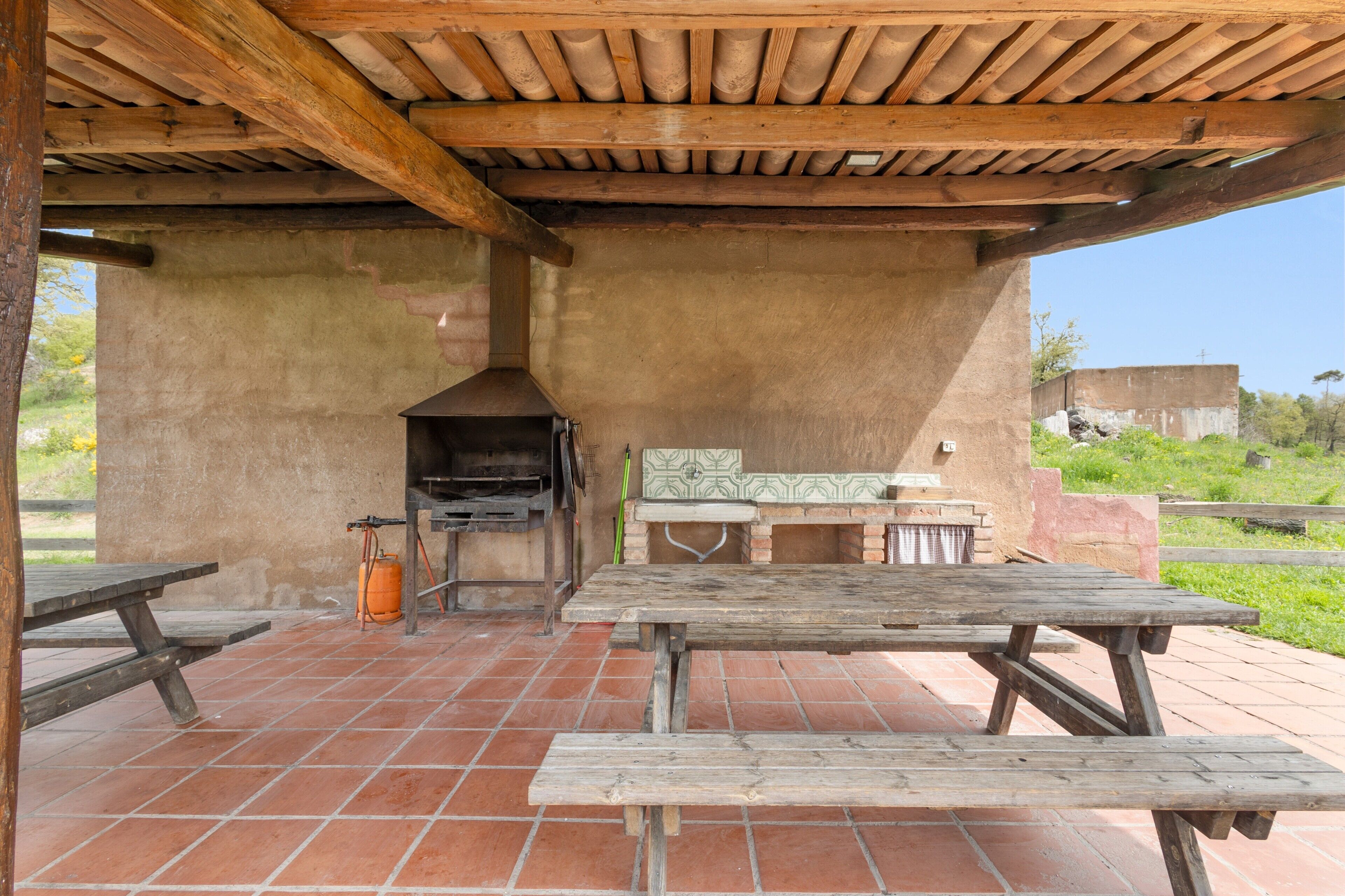 Un patio al aire libre con bancos de madera, una parrilla y suelo de baldosas.