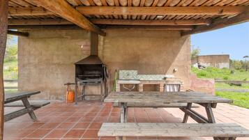 Un patio al aire libre con bancos de madera, una parrilla y suelo de baldosas.