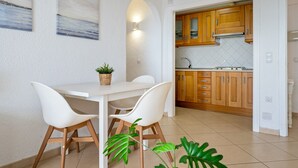Una cocina moderna con armarios de madera, encimera blanca y un comedor con mesa y sillas blancas.