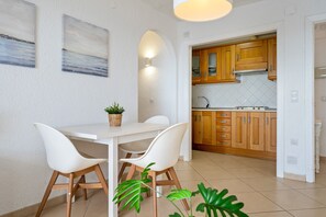 Eine moderne Küche mit Holzschränken, einer weißen Arbeitsplatte und einem Essbereich mit weißem Tisch und Stühlen.