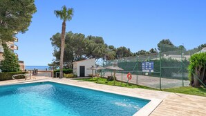 Una piscina con muelle de madera, un salvavidas y un área cercada con un cartel.