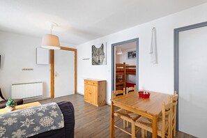 Tunnelmallinen olohuone, jossa on puinen ruokapöytä, sohva ja pieni kaappi.