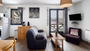 A modern living space with a sofa, a coffee table, a television, and a window with a view. - Apartment 'Capcir' with Mountain View, Shared Terrace and Wi-Fi (Les Angles)