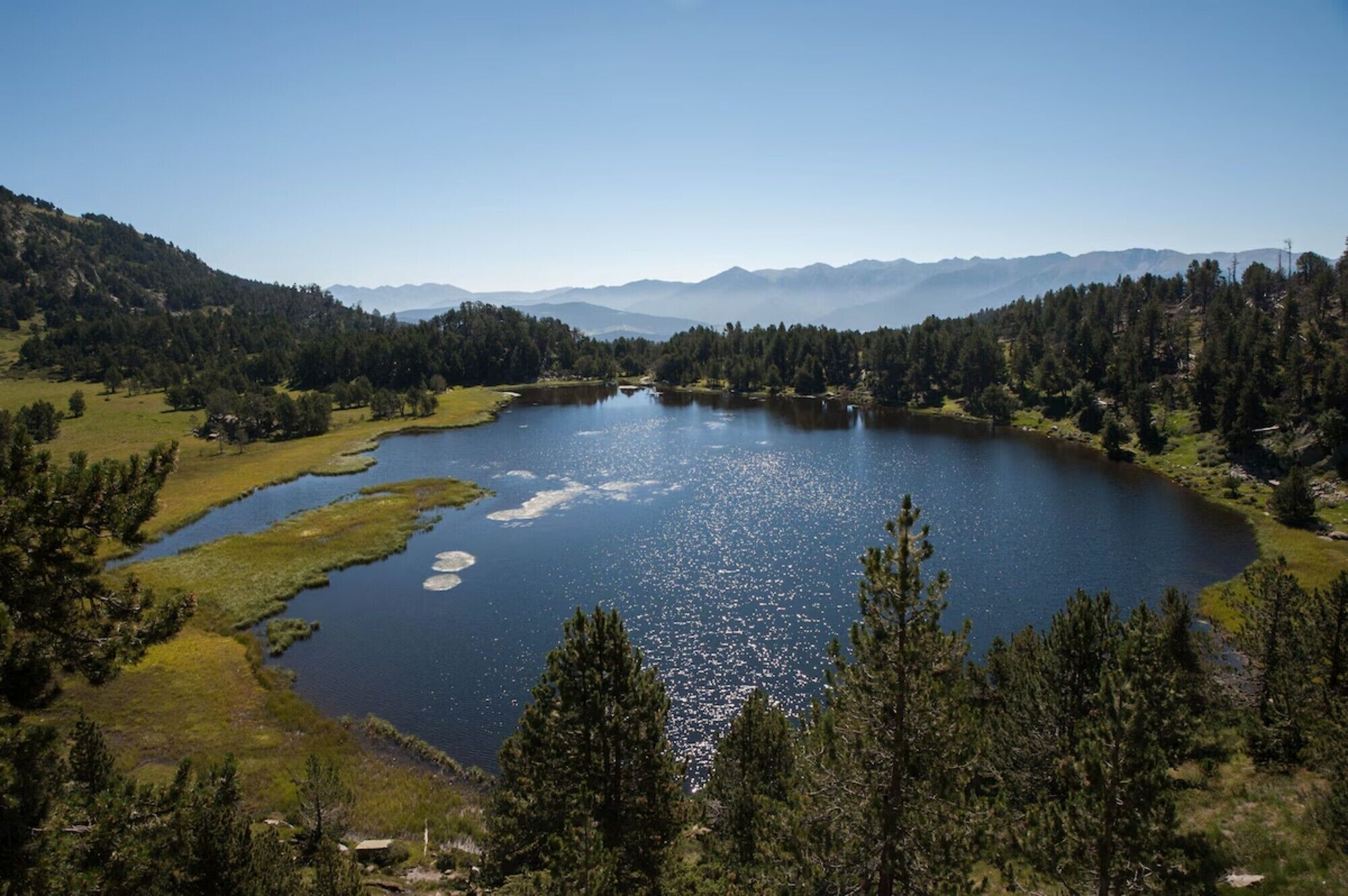 A lake surrounded by forested hills and mountains.