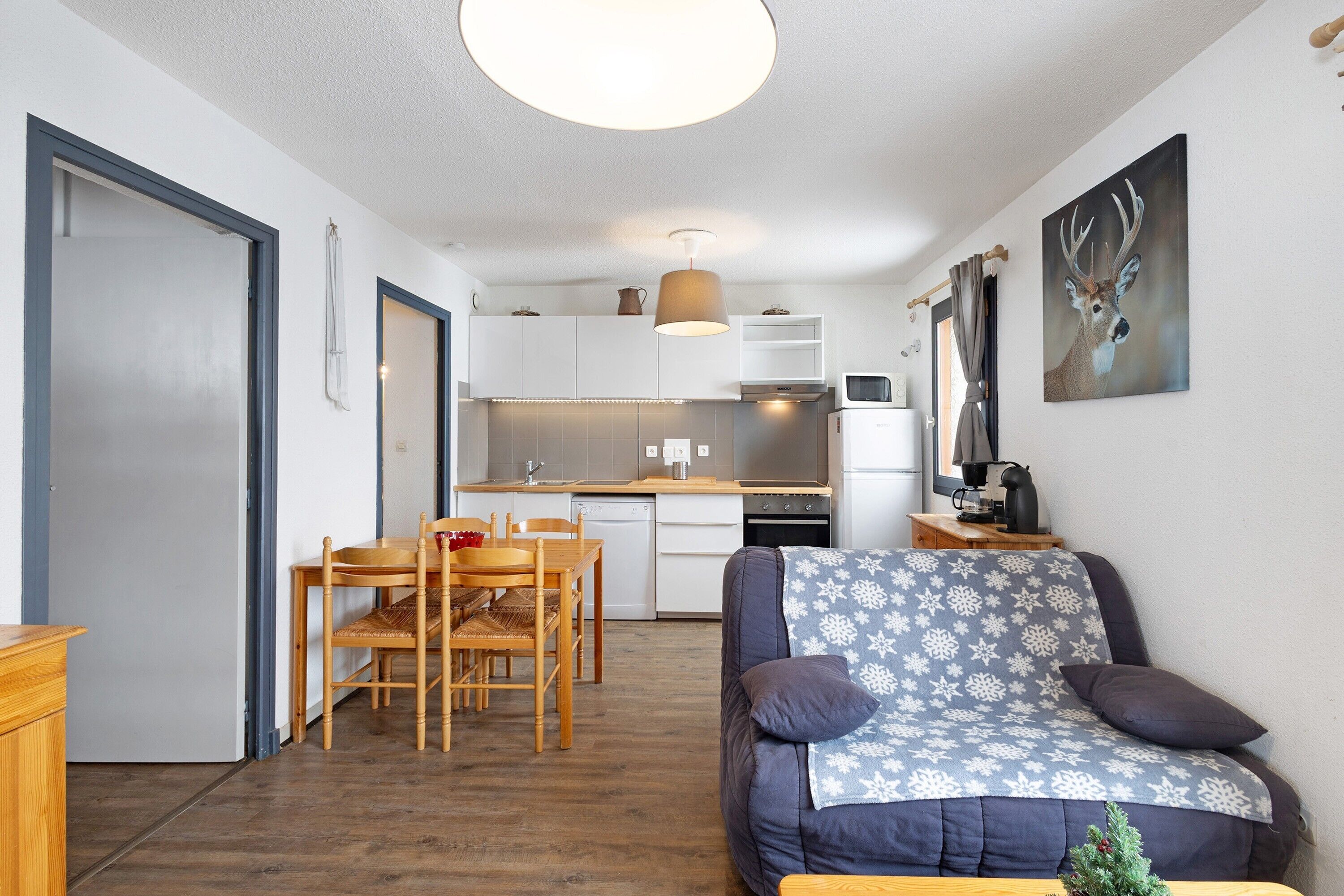 Un ambiente compatto con angolo cottura, zona pranzo e divano con coperta decorata.