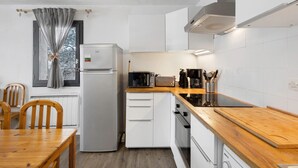 A compact kitchen with white cabinets, a wooden countertop, a built-in microwave, and a refrigerator. - Apartment 'Cerdagne' with Mountain View, Shared Terrace and Wi-Fi (Les Angles)