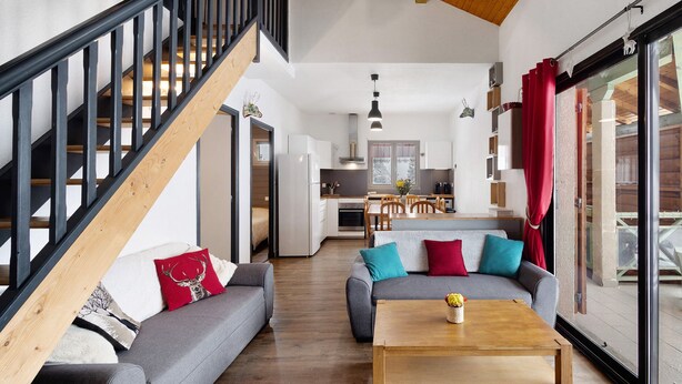 A spacious living area with a staircase, a kitchen, and a dining area.