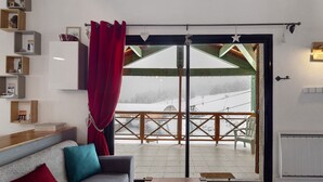 A cozy living room with a sofa, a coffee table, and a view of a snowy outdoor balcony.