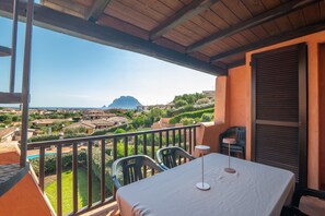 Un balcón con mesa y sillas, con vista a una zona residencial y una montaña al fondo.