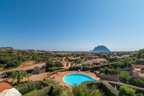 Un resort con piscina, rodeado de exuberante vegetación y edificios de estilo mediterráneo.