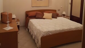 Quarto com cama, mesa de cabeceira, cômoda, ar-condicionado na parede e lustre.