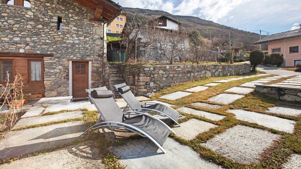 Un edificio in pietra con una porta in legno, un balcone e un muro in pietra.