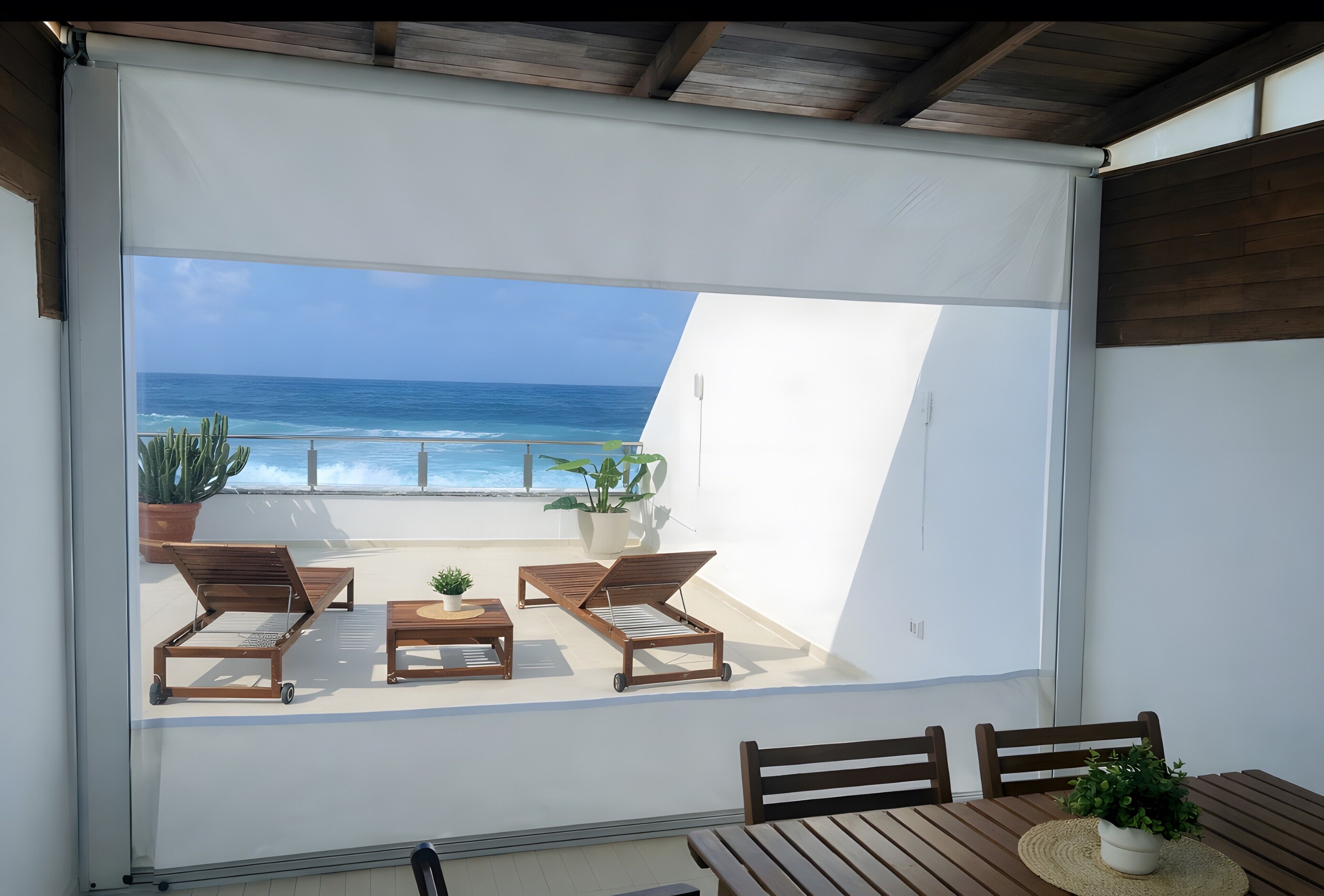 Ein Balkon mit Blick auf das Meer, Holzmöbel und Kübelpflanzen.