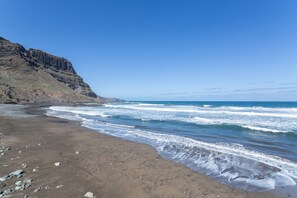A beach with rocky terrain and a cliff.