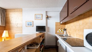 Een kleine keuken met een houten aanrecht, een wasmachine en een televisie.