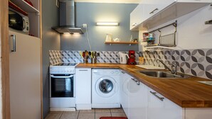 Une cuisine compacte équipée d’une cuisinière, d’un four à micro-ondes, d’un lave-linge et d’un évier.