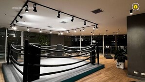 A boxing ring in a modern room with a wooden floor, large windows, and a visible plant. - 3 Dormitorios en el Edificio ONE Quito (Quito)