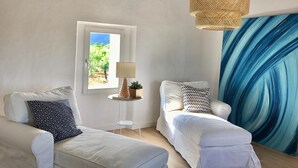 A room with two white sofas, a small table with a lamp, a window with a view of greenery, and a blue curtain. - Holiday Home 'Son Pelai Menut' with Mountain View, Wi-Fi and Air Conditioning (Illes Balears)