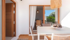A modern dining area with a white table, chairs, and a bowl of cookies. - Villa 'Can Americano, 4 with Mountain Views, Wi-Fi and Air Conditioning (Illes Balears)