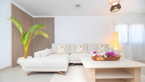 A modern living room with a sectional sofa, a coffee table with flowers, and a potted plant. - Villa 'Can Americano, 4 with Mountain Views, Wi-Fi and Air Conditioning (Illes Balears)