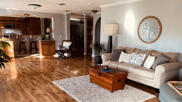 Amplia sala de estar con suelo de madera, un sofá, una mesa de centro y un comedor al fondo.
