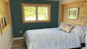 Un dormitorio con una cama, una ventana y paneles de madera en las paredes.