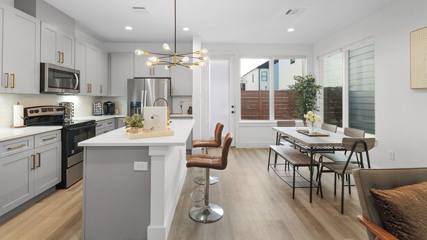 A modern kitchen with a central island, stainless steel appliances, and a dining area with a bench and table. - Modern Heights Townhome 3BR with Fast Wifi & Free Park (Houston)