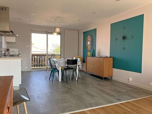 A modern kitchen with a stove, dining table, chairs, and a view to the outside. - Crevette Saint Gilles Croix de Vie (SAINT GILLES CROIX DE VIE)
