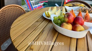 Un tavolo di legno con una ciotola di frutta, una sedia e una piscina sullo sfondo.