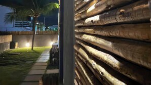 Un muro in legno con travi orizzontali, una palma e un vialetto.