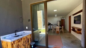 Una cucina moderna con lavello integrato, un piccolo sgabello e una zona pranzo con tavolo e sedie.