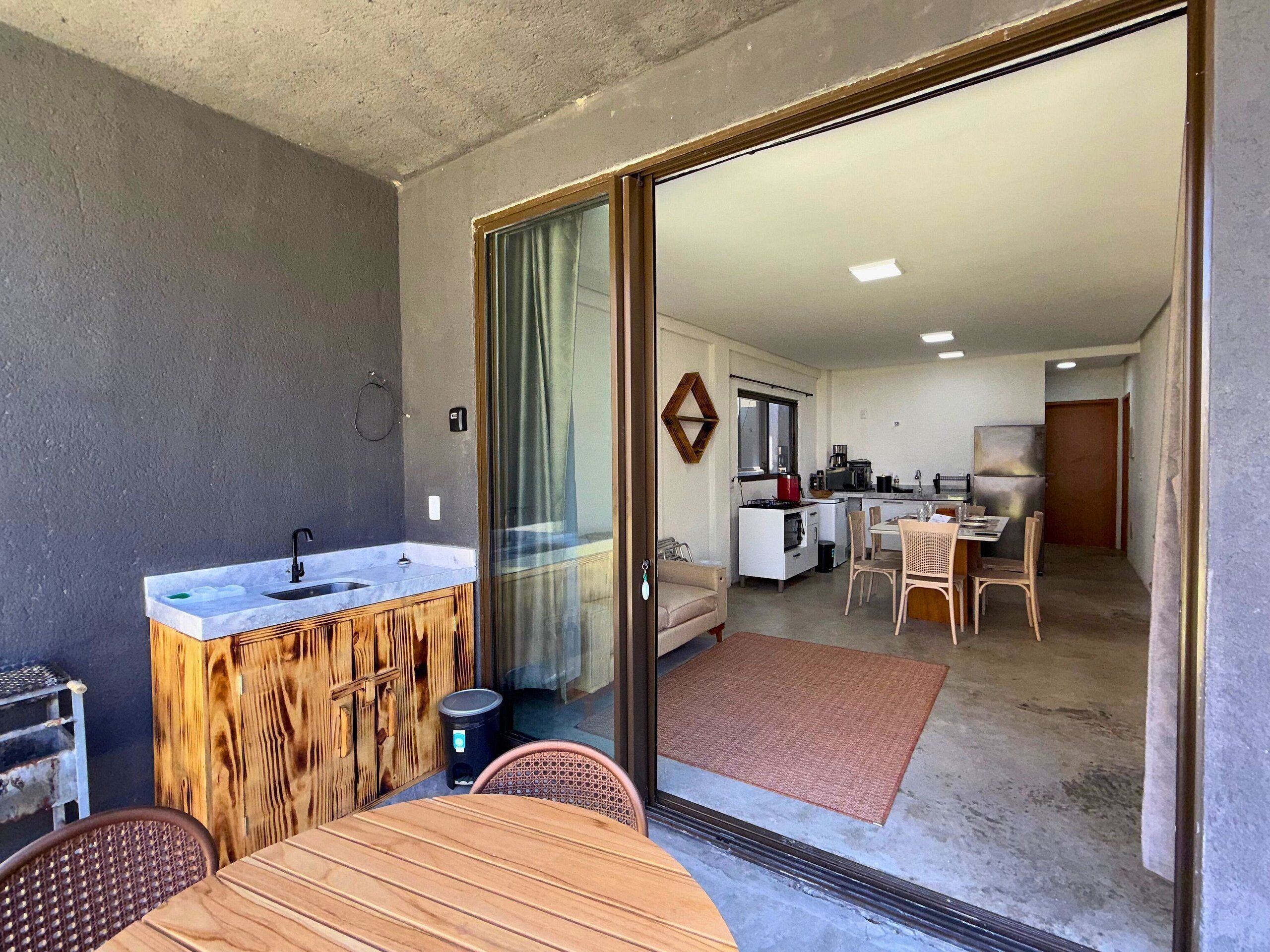 A compact living space with a kitchenette, a dining area, and a sliding glass door leading to a balcony.