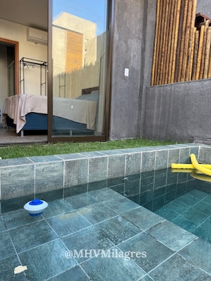 Una piscina con bordes de azulejos, una manguera y un recipiente azul.
