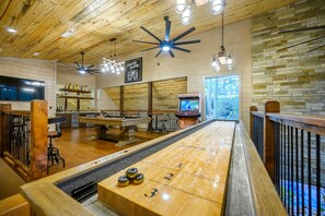 A billiards table, ceiling fans, and a bar area with bottles.