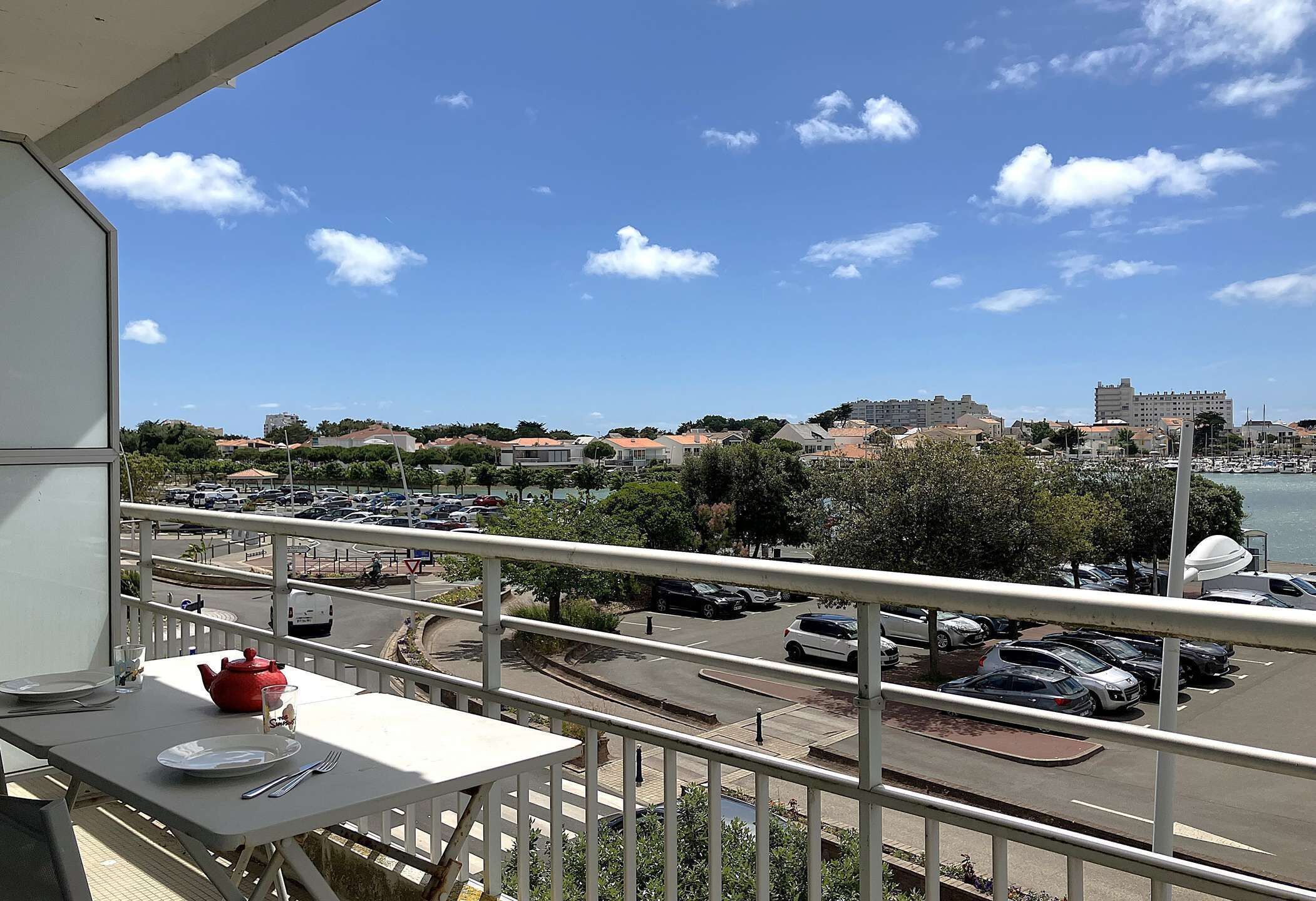 A balcony with a table, a red teapot, and a glass of water.