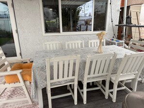 A dining area with a table set for six, surrounded by white chairs, a patterned tablecloth, and a vase with dried flowers. - Wildwood Regional Park House - World Cup Ready --75 Miles to SoFi (Thousand Oaks)