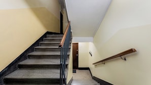 A staircase with a wooden handrail and a carpeted landing.
