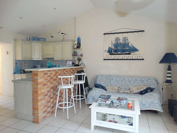 A compact living space with a kitchen area, a dining bar, and a sofa.