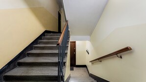 A staircase with a wooden handrail and a carpeted landing. - Underground Mystique Apartment (Kraków)