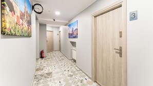 A hallway with patterned flooring, a clock, and doors numbered 2 and 3. - Underground Mystique Apartment (Kraków)