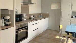 Une cuisine moderne équipée d’une machine à café Bosch, d’un four à micro-ondes et d’un four encastré.