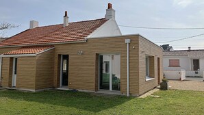 Une maison de plain-pied avec un toit en tuiles, une porte d’entrée et une porte-fenêtre coulissante.