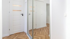 A hallway with white doors and a wooden herringbone floor.